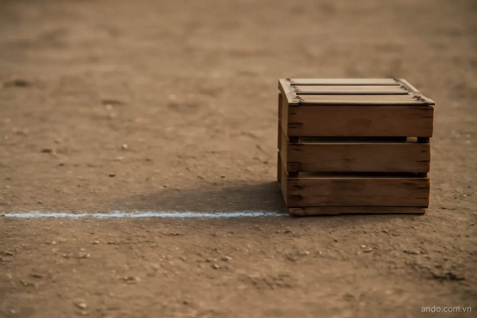 A single chalk line drawn across bare ground with a crate placed to one side of it and an empty space to the other, straight on view, no text