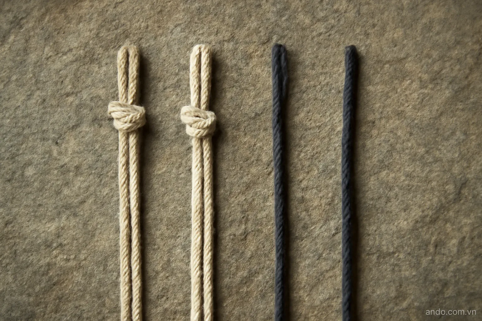 Four short cords laid parallel on stone, two knotted and two loose, overhead view, no text