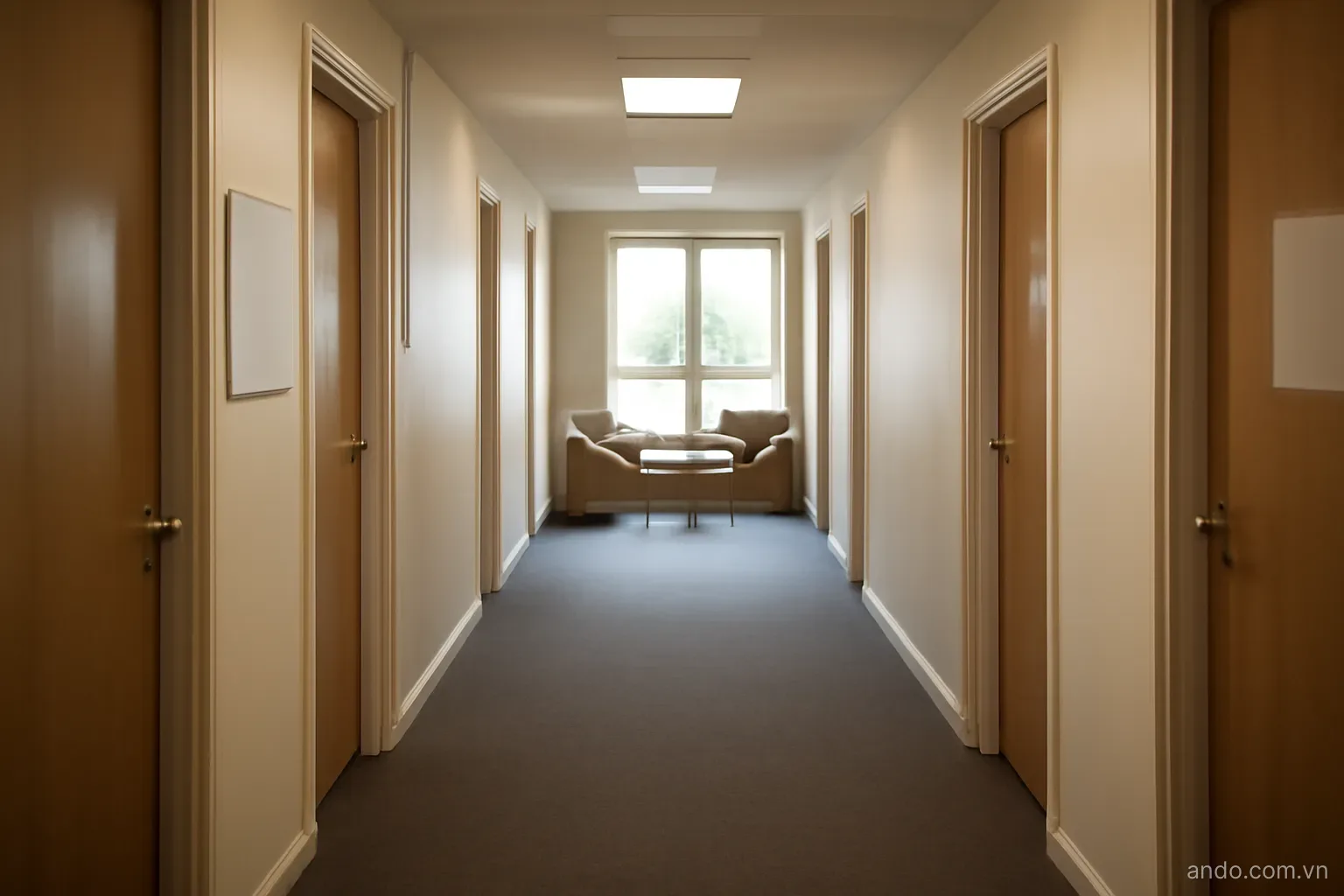 A student dormitory corridor with doors on both sides and a shared common area at the end, eye level, no text